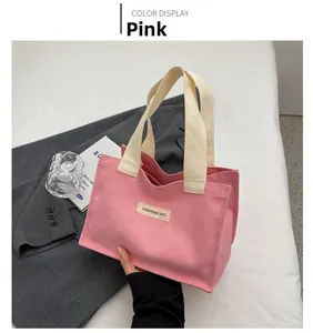 Détail d'un sac cabas en toile rose avec écusson FASHIONS BAG et poignées tissées