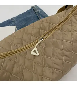 Detail of smooth metal zipper and triangle puller on khaki quilted crossbody bag