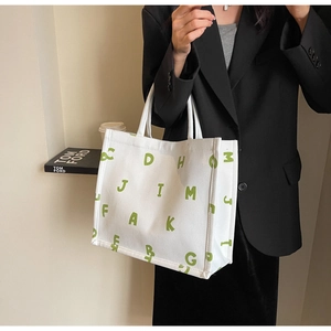 Detail of white canvas tote bag with green letters and durable fabric texture