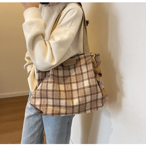 Detail of checkered wool tote bag showing leather fashion patch and plaid rabbit charm