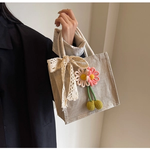 Close-up of linen tote bag featuring crochet flowers and a large lace bow decoration