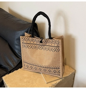 Close-up of a large linen tote bag with black geometric patterns and rope handles