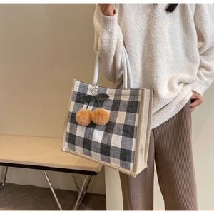 Detail of waffle tote bag featuring checkerboard canvas and plush cherry charm