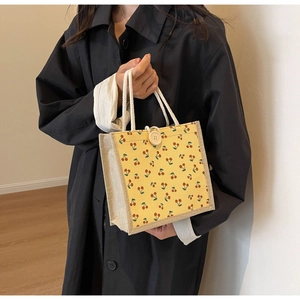 Detail of yellow corduroy tote bag with cherry prints and woven rope handles