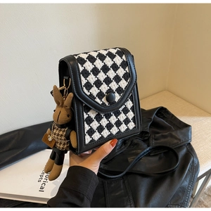 Detail of vintage houndstooth mini crossbody bag with cute rabbit plush accessory