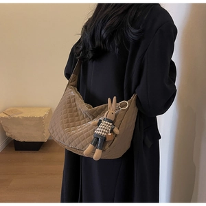 Détail d'un sac matelassé marron avec un joli pendentif en forme de lapin en tricot
