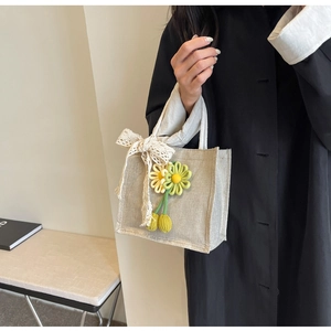 Close-up of linen lunch bag with white lace bow and handmade knit flower pendants