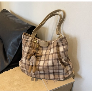 Detail of checkered tote bag with fashion label and cute bunny plush accessory