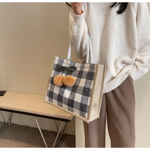 Close-up of black and white checkered linen tote with cotton rope handles and cherry charm