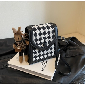 Close-up of houndstooth mini crossbody bag with round button and brown rabbit charm
