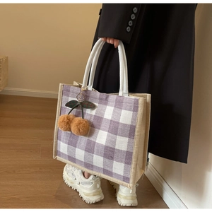 Detail of purple waffle pattern tote bag with jute trim and plush cherry charm decoration