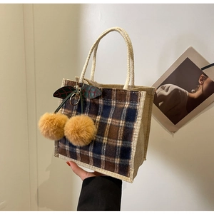 Detail of checkered mini tote bag with cherry pom-pom charm and rustic jute fabric texture