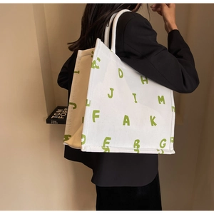 Close-up of durable canvas tote bag featuring green block letter typography design