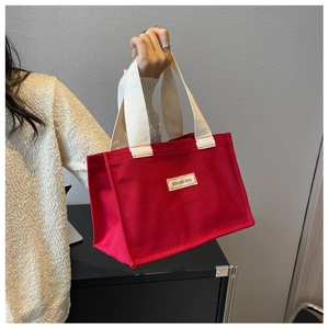 Gros plan du sac cabas en toile rouge avec anses blanc cassé et étiquette tissée