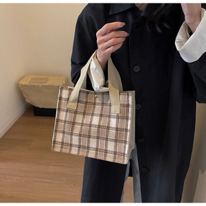 Détail d'un sac cabas vintage à carreaux marron avec anses tissées et bouton doré
