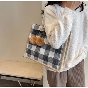 Detailed view of the checkered linen tote bag with a plush cherry charm decoration