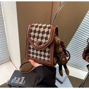 Close-up of houndstooth mini crossbody bag with a cute rabbit doll charm attachment