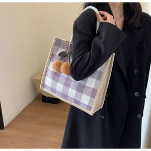 Detail of waffle plaid tote bag in purple and white with brown cherry pompom charm