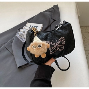 Détail du sac en cuir croco avec broderie papillon rose et breloque en peluche douce