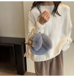 Close-up of plush rabbit crossbody bag in grey-purple with golden chain and doll pendant