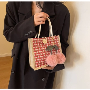 Detail of red checkered woven handbag with rope handle and pink faux fur cherry charm