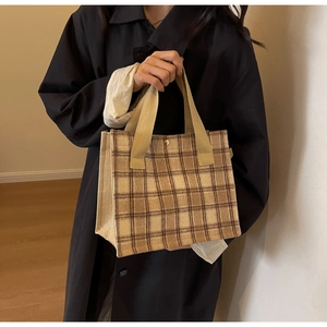 Détail du sac cabas à carreaux montrant la texture du tissu et le bouton-pression doré