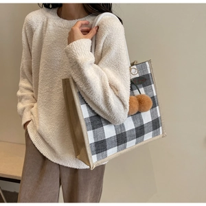 Detailed close-up of a large checkered linen tote bag with a plush cherry charm accessory