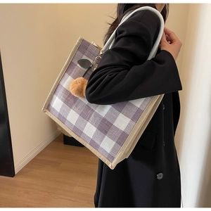 Detailed look at purple waffle pattern tote bag with woven straps and orange pompom charm