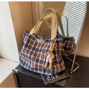 Detail of wool tote bag with blue plaid pattern and cute rabbit doll keychain charm