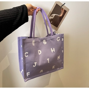 Detail of purple canvas tote bag with white lettering and thick rope handles