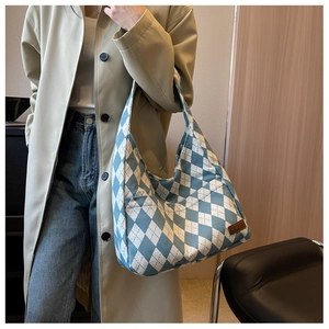 Detail of blue and white diamond pattern canvas bag with a brown leather logo label