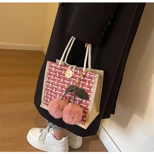 Detail of red checkered woven tote bag with cute cherry pom-poms and cotton rope handles