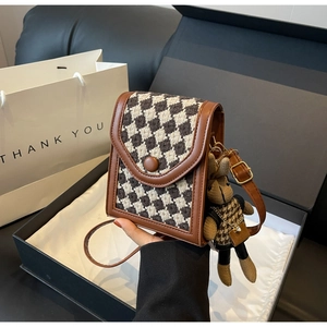 Detailed shot of houndstooth crossbody bag with a cute rabbit charm and leather trim
