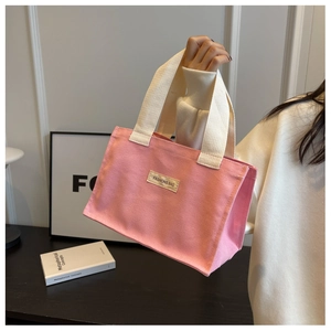 Détail d'un sac cabas en toile rose avec poignées crème et étiquette de mode stylée