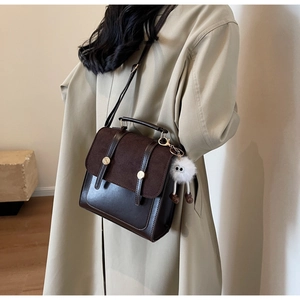 Detail of vintage coffee backpack featuring suede texture and decorative plush pendant