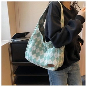 Detail of green argyle canvas shoulder bag featuring a brown fashion leather patch