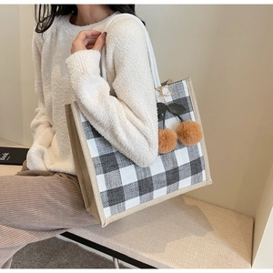 Close-up of black and white checkered linen tote bag with brown plush cherry charm