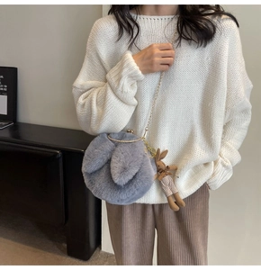 Detail of gray plush rabbit ear purse with golden metal clasp and chain strap
