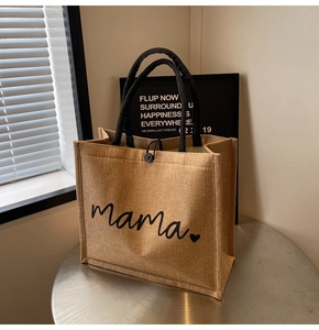 Close-up of linen tote bag featuring mama text and black woven handle with button closure