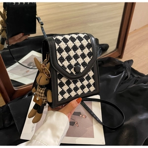 Close-up of houndstooth crossbody bag with black leather trim and cute rabbit charm