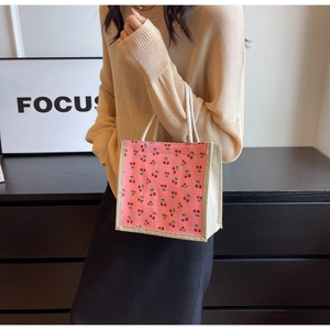 Detail of pink corduroy tote bag with cherry floral pattern and woven rope handles