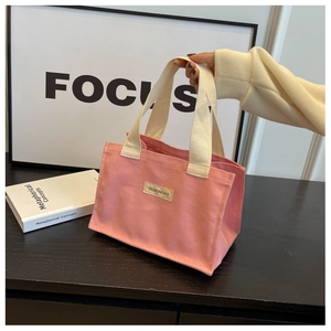 Détail du sac cabas en toile rose avec poignées tissées et étiquette FASHIONS BAG