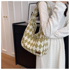 Detail of green diamond-quilted tote bag featuring wide strap and FASHION leather tag