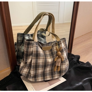 Close-up of wool plaid tote bag featuring a FASHION leather patch and cute rabbit charm