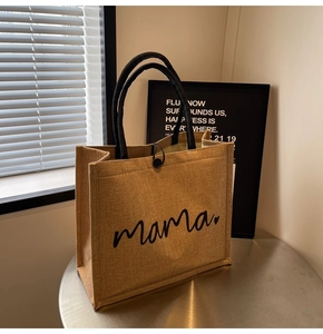 Detail of jute tote bag showing mama print with black handles and button closure
