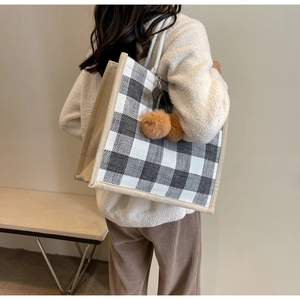 Close-up of large waffle tote bag side view with cherry plush charm and reinforced trim