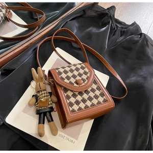 Detailed shot of vintage houndstooth crossbody bag with cute bunny doll charm