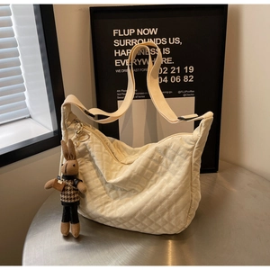 Sac bandoulière matelassé beige en nylon avec surpiqûres en losange et pendentif lapin