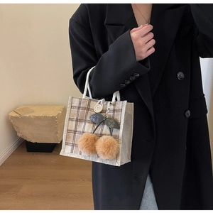 Detail of vintage plaid bento bag with brown plush cherry charms and woven rope handles