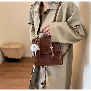 Detail of vintage brown suede satchel with metal buckles and plush monster charm